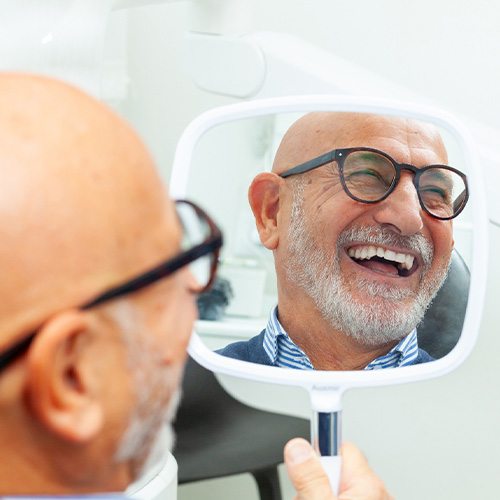 Man with black glasses smiling in reflection in mirror
