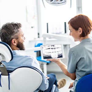 Smiling dental assistant and patient looking at X-ray