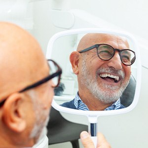 Man with black glasses smiling in reflection in mirror