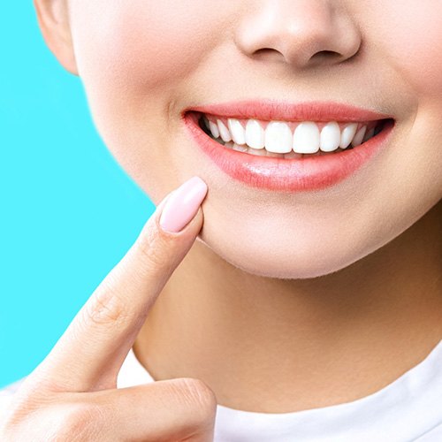 Nose-to-neck view of woman pointing to her bright white smile